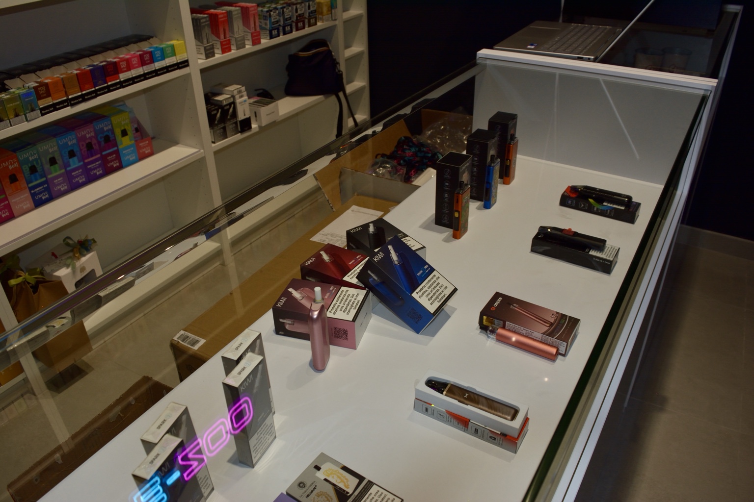 Il banco espositivo di VAPEZOO con il riflesso dell’insegna al neon